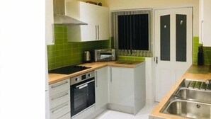 A compact kitchen with white cabinets, a stove, oven, and a microwave. - Townhouse @ Westminster St (Crewe)