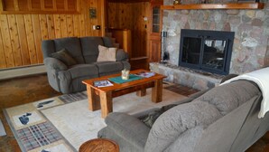 A cozy living room with a fireplace, a sofa, a coffee table, and a rug with a fish pattern.