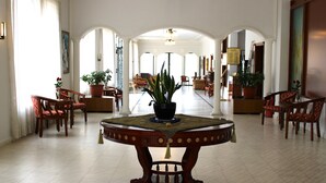 A spacious lobby with a central round table, multiple seating areas, and potted plants. - Al Sakhra Hotel (Bhamdoun)