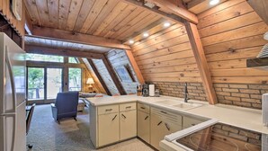 A kitchen with wooden beams, a central island, and a view through the windows. - Lake Pepin Cottage w/ Decks + Private Beach! (Stockholm)