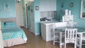 Ein kleines Zimmer mit Bett, einer Küchenzeile und einem Essbereich.