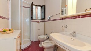 Et badeværelse med bruser, toilet og vask.