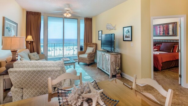 Een ruime woonkamer met balkon, een televisie en een eethoek met tafel en stoelen.