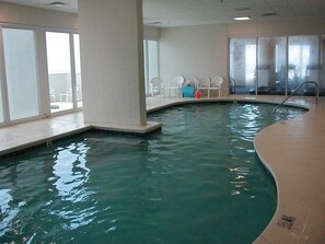 Relax by the serene oval-shaped pool, surrounded by a spacious area with high ceilings.