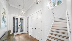 Un pasillo con pisos de madera, puertas blancas y una escalera.