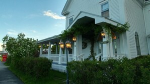 A white house with a porch, a 'VACANCY' sign, and a street lamp.
