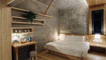 A cozy bedroom with a wooden bed, a desk with a lamp, and shelves with decorative items.