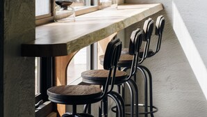 A modern kitchen with a long countertop, black bar stools, and a view of greenery outside. - Sun Moon Lake Residence 8 (Yuchi)