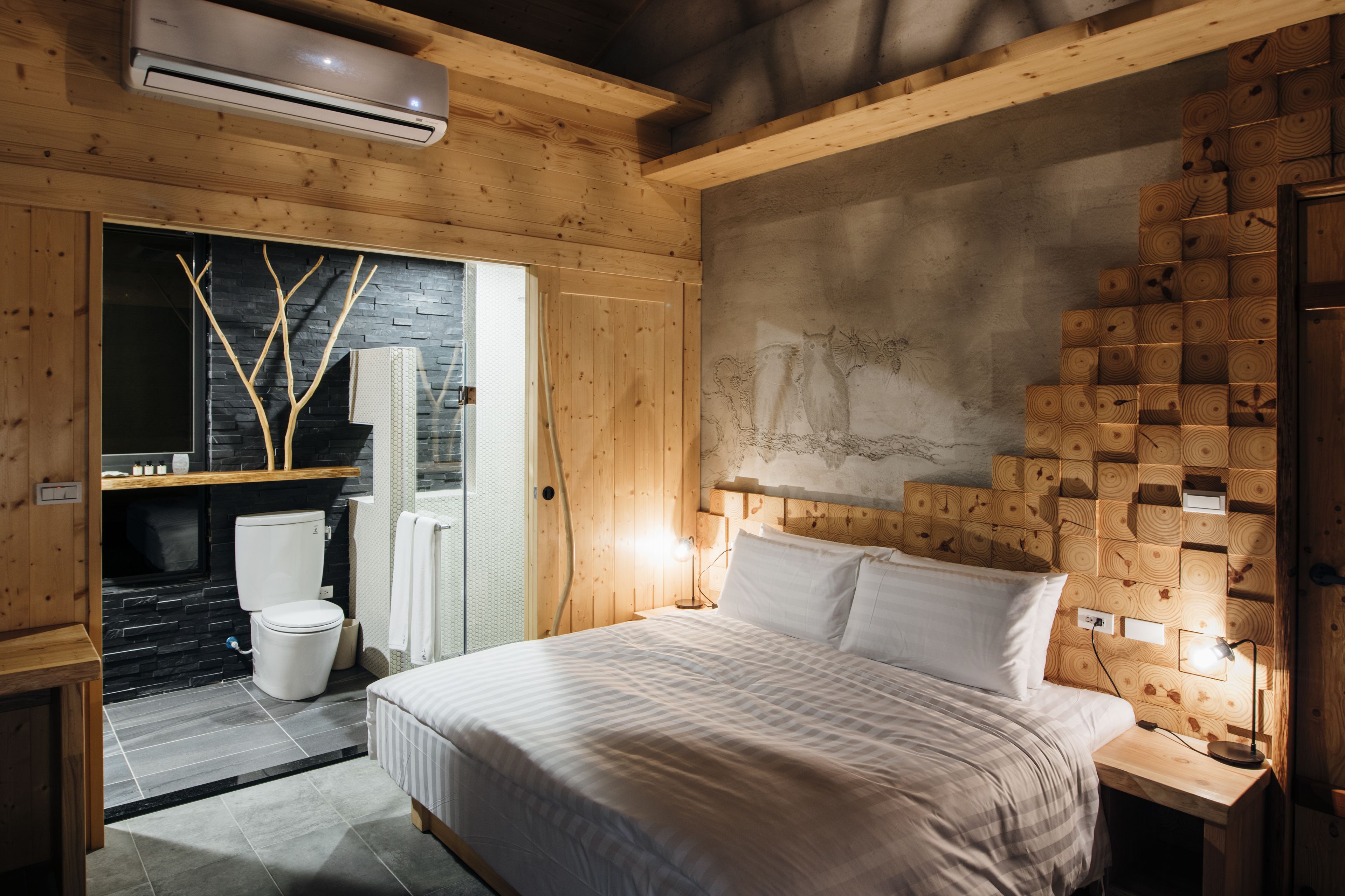 Un dormitorio con cama, cabecero de madera y una lámpara fijada a la pared.
