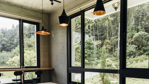 A long wooden table with stools, large windows with a view of greenery, and pendant lighting. - Sun Moon Lake Residence 8 (Yuchi)