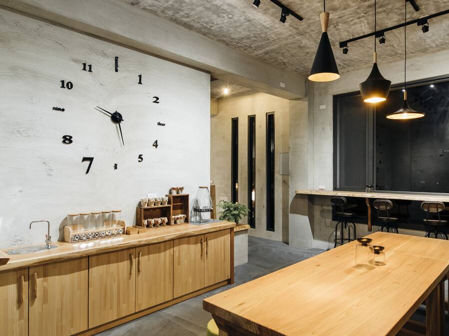 Una cocina moderna con encimera de madera, un reloj grande e iluminación colgante.