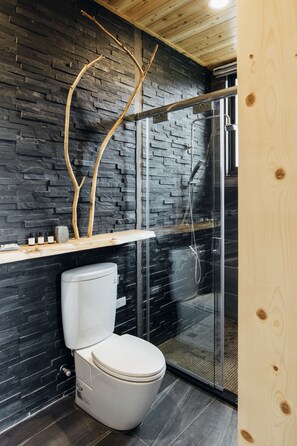 A modern bathroom with a stone wall, a wooden ceiling, a toilet, and a glass shower enclosure. - Sun Moon Lake Residence 8 (Yuchi)