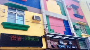 A multi-story building with colorful facades, air conditioning units, and a digital signboard. - Fubin Hostel (Hengchun)