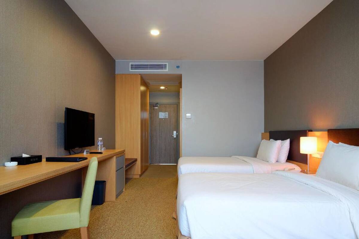 Ein Hotelzimmer mit einem Bett, einem Schreibtisch, einem Sessel, einem Fernseher und einer Lampe.