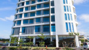 A modern hotel building with a curved facade, multiple balconies, and a clear sky in the background. - Hotel N°5 (Kota Kinabalu)