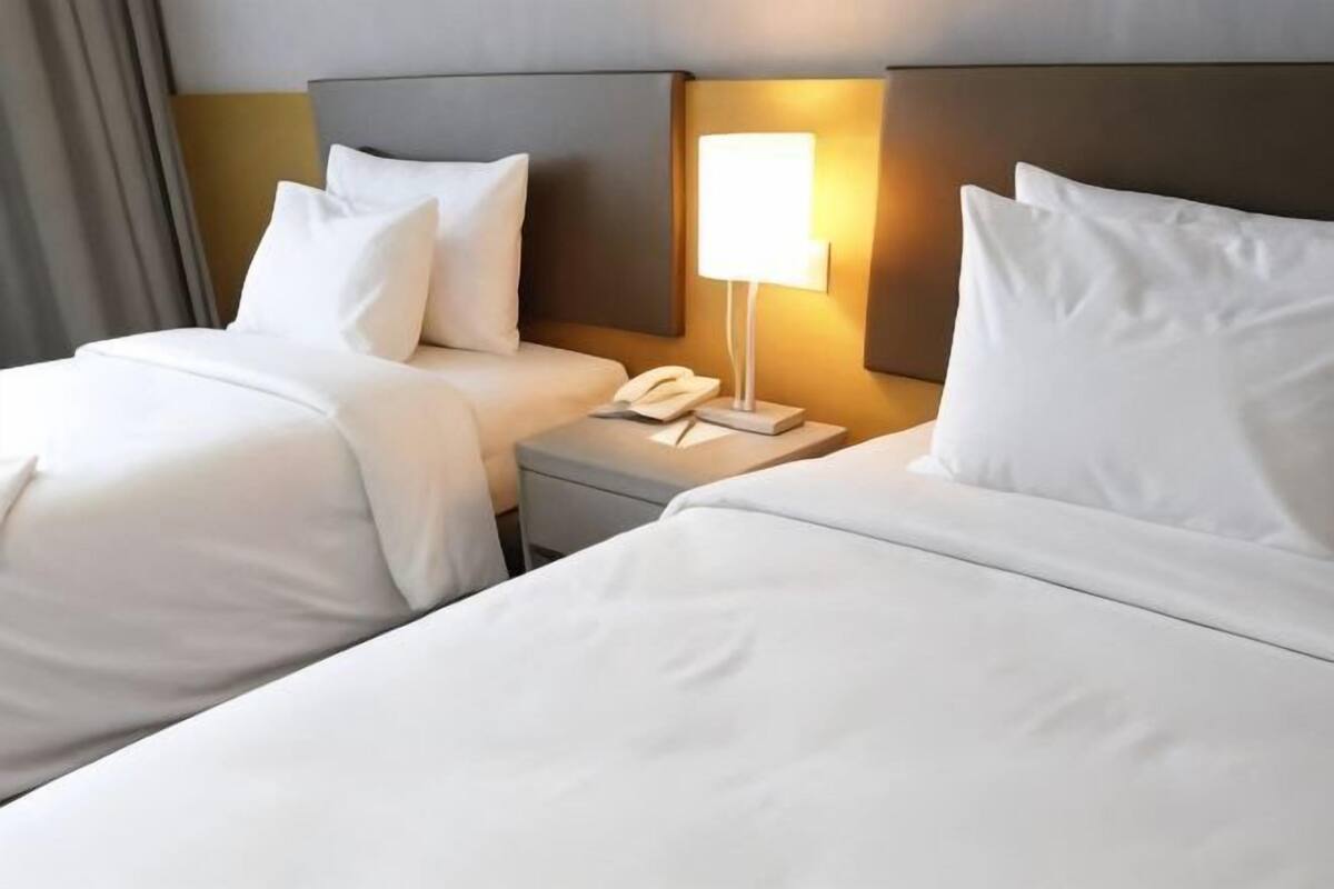 Ein Hotelzimmer mit zwei Betten, einem Nachttisch mit Lampe und einem Telefon.