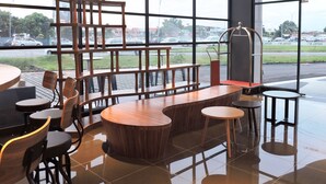 A modern interior with a wooden bar area, seating, and large windows offering a view of the street. - Hotel N°5 (Kota Kinabalu)