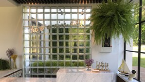A reception area with a marble counter, a glass block wall with 'have a nice day!' written on it, and a large green plant. - Hotel Everyday Life (Hengchun)