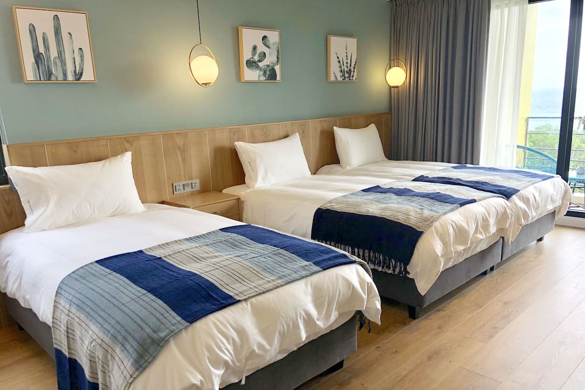 A hotel room with two beds, wooden headboards, white bedding, and artwork on the walls.