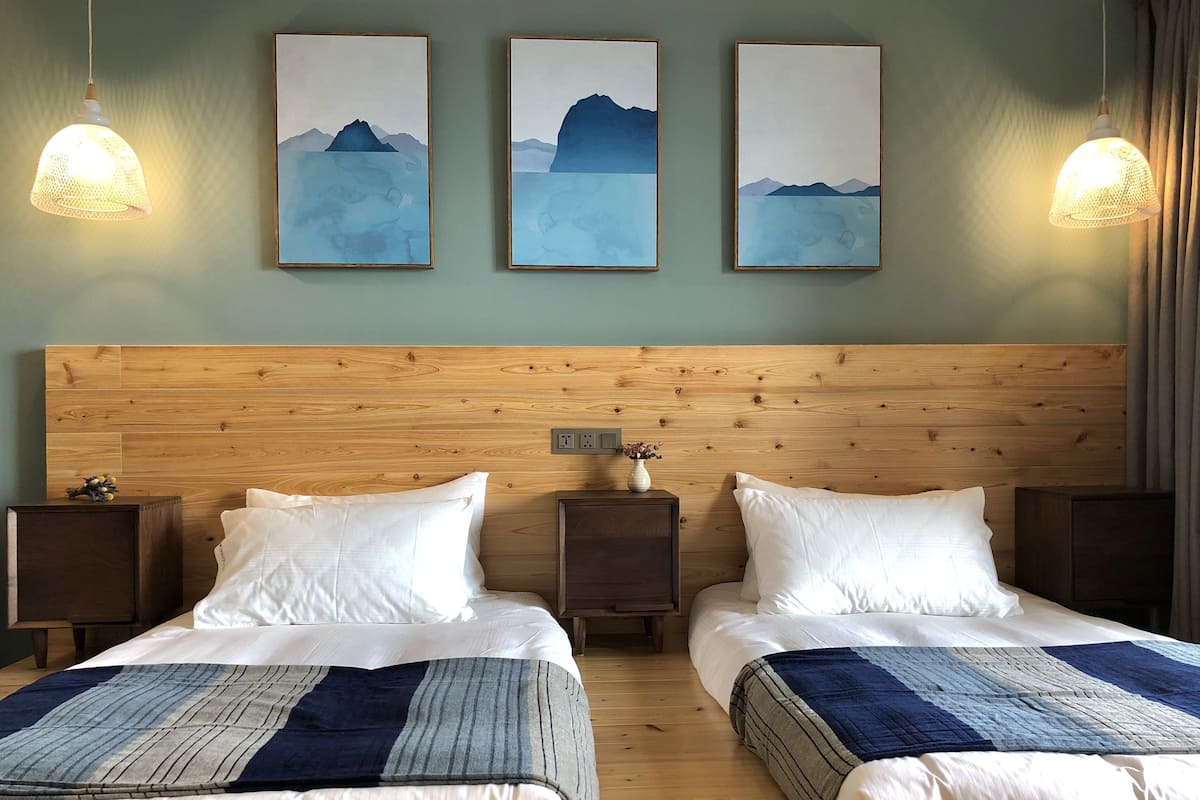 A double room with two beds, wooden headboard, bedside tables, and wall-mounted artwork.