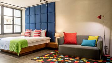 Une chambre moderne avec un lit, un canapé, un tapis coloré et une fenêtre.