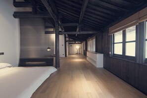 A hallway with wooden flooring and a sloped ceiling, leading to a room with a bed and a window. - Hangzhou Utea Guesthouse (Hangzhou)