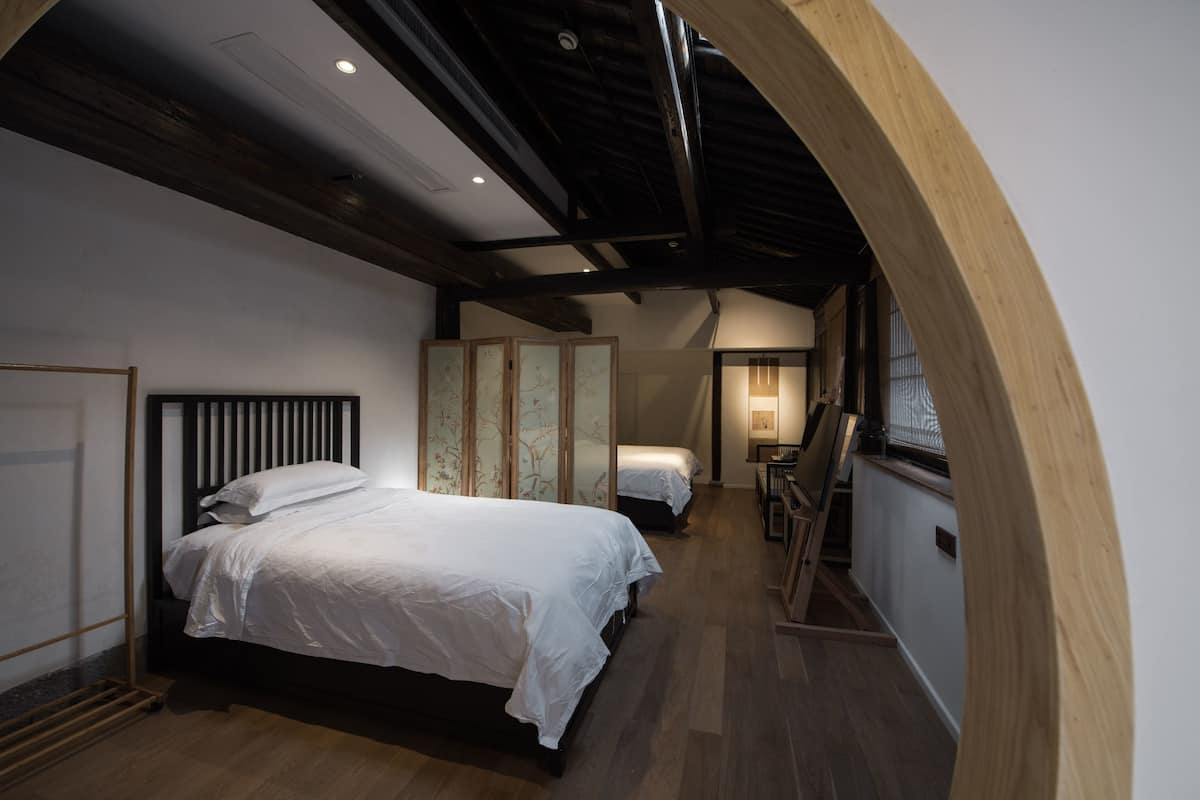 Un dormitorio con una cama grande, techo de madera y una puerta corrediza.