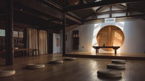 A spacious room with a wooden floor, a circular wooden structure, and a bench. - Hangzhou Utea Guesthouse (Hangzhou)