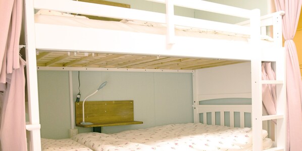 A bunk bed room with a wooden headboard, a bedside lamp, and a floral-patterned bedspread.