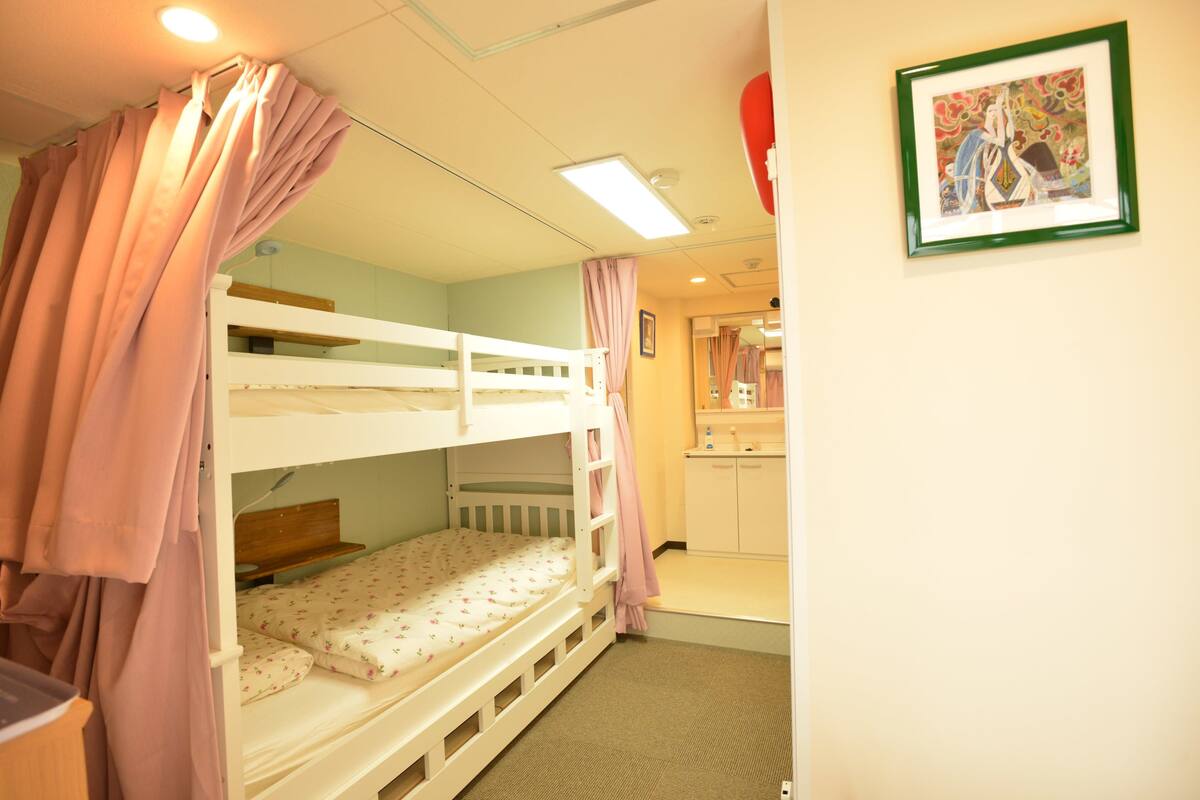 A bunk bed room with a small desk and a mirror.