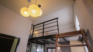 Ein mehrgeschossiges Interieur mit einer Treppe, einer Holzleiter und einer hängenden Leuchte.