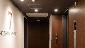 A hallway with a number 7 sign, an elevator, and a carpeted floor. - Belken Hotel Kanda (Tokyo)