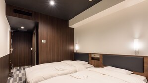 A hotel room with two beds, a wooden headboard, a bedside table, and a wall-mounted TV. - Belken Hotel Kanda (Tokyo)