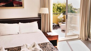 A hotel room with a large bed, a nightstand, a lamp, and a view of a balcony with outdoor furniture. - Ribera Sur Mar del Plata (Mar del Plata)
