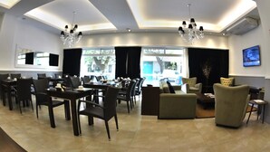 A spacious lobby with a modern chandelier, comfortable seating, and a television on the wall. - Ribera Sur Mar del Plata (Mar del Plata)