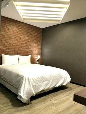 A modern bedroom with a brick accent wall, a large bed, and a unique ceiling light fixture. - Ching She Hotel (Tainan)
