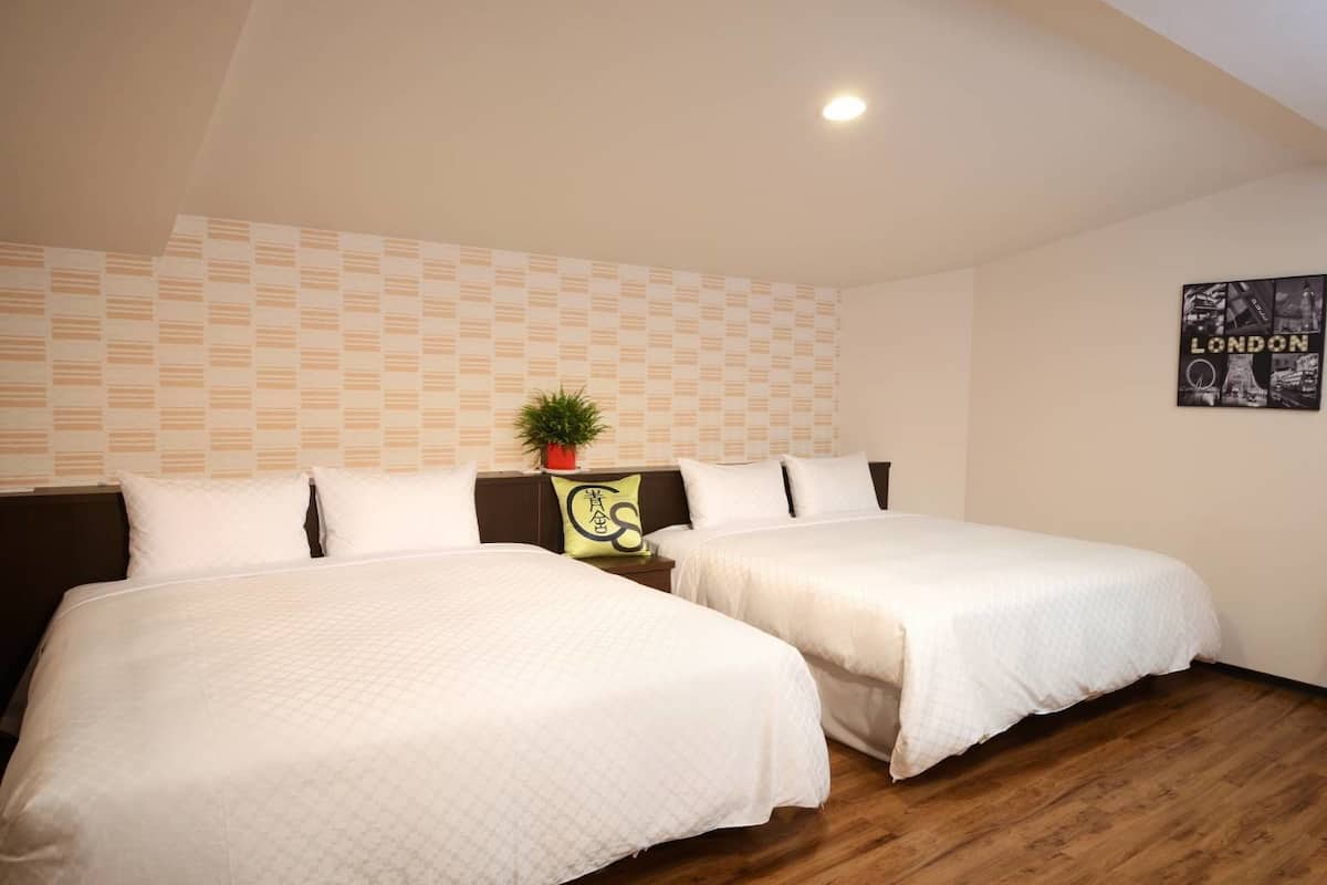 Habitación de hotel con dos camas, un papel tapiz estampado, una planta y un cartel de Londres.