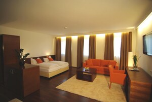 Una habitación de hotel moderna con una cama grande, un sofá, una mesita de centro y un televisor.