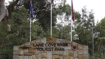 A stone sign with "LANE COVE RIVER TOURIST PARK" and a logo for "PARKS & WILDLIFE" on a stone wall.