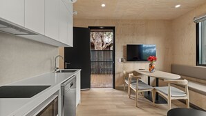 Uma cozinha moderna com forno embutido, área de refeições com banco e cadeiras, e TV montada na parede.