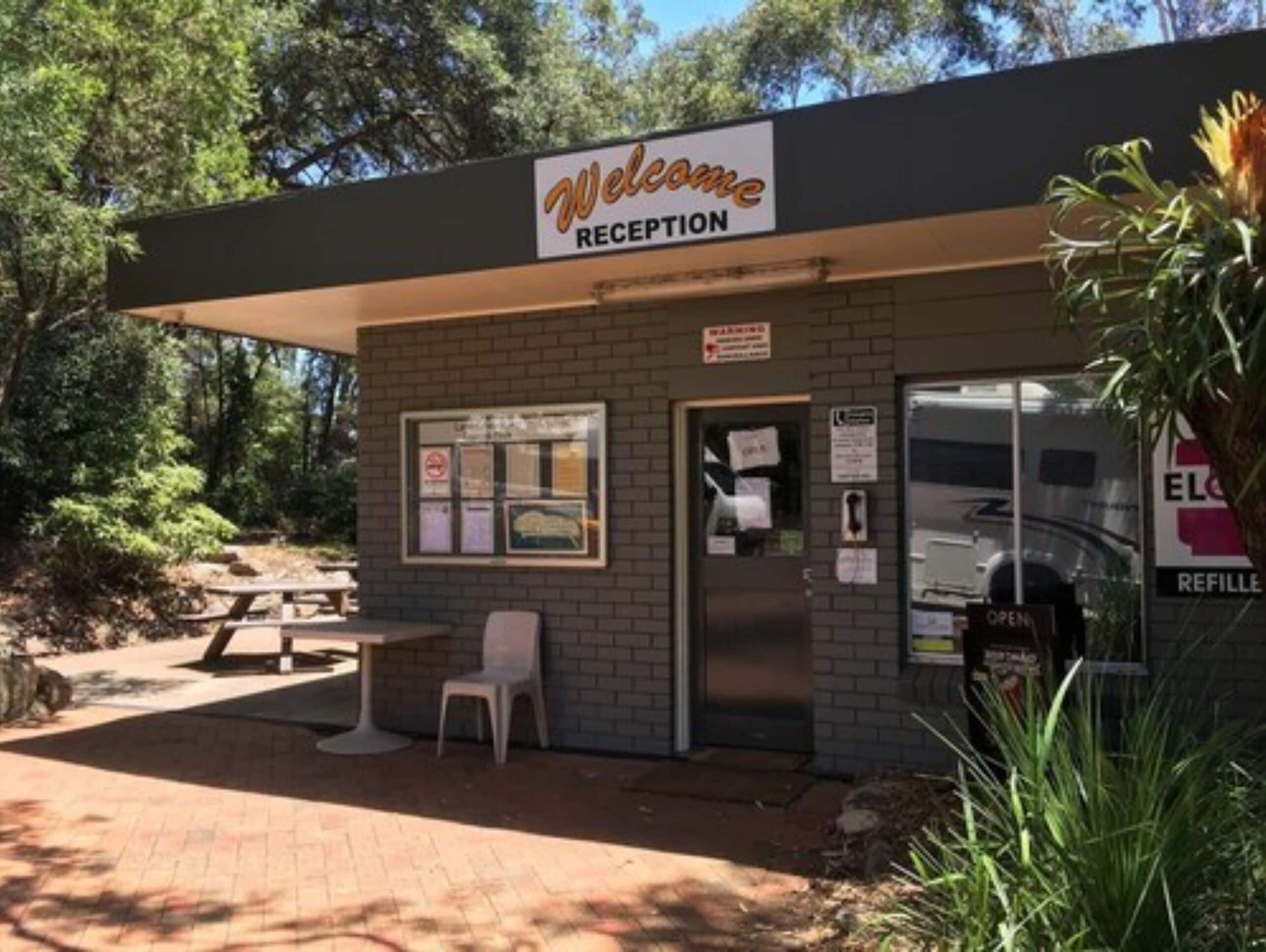 A reception area with a 'Welcome' sign, a picnic table, and a bench.