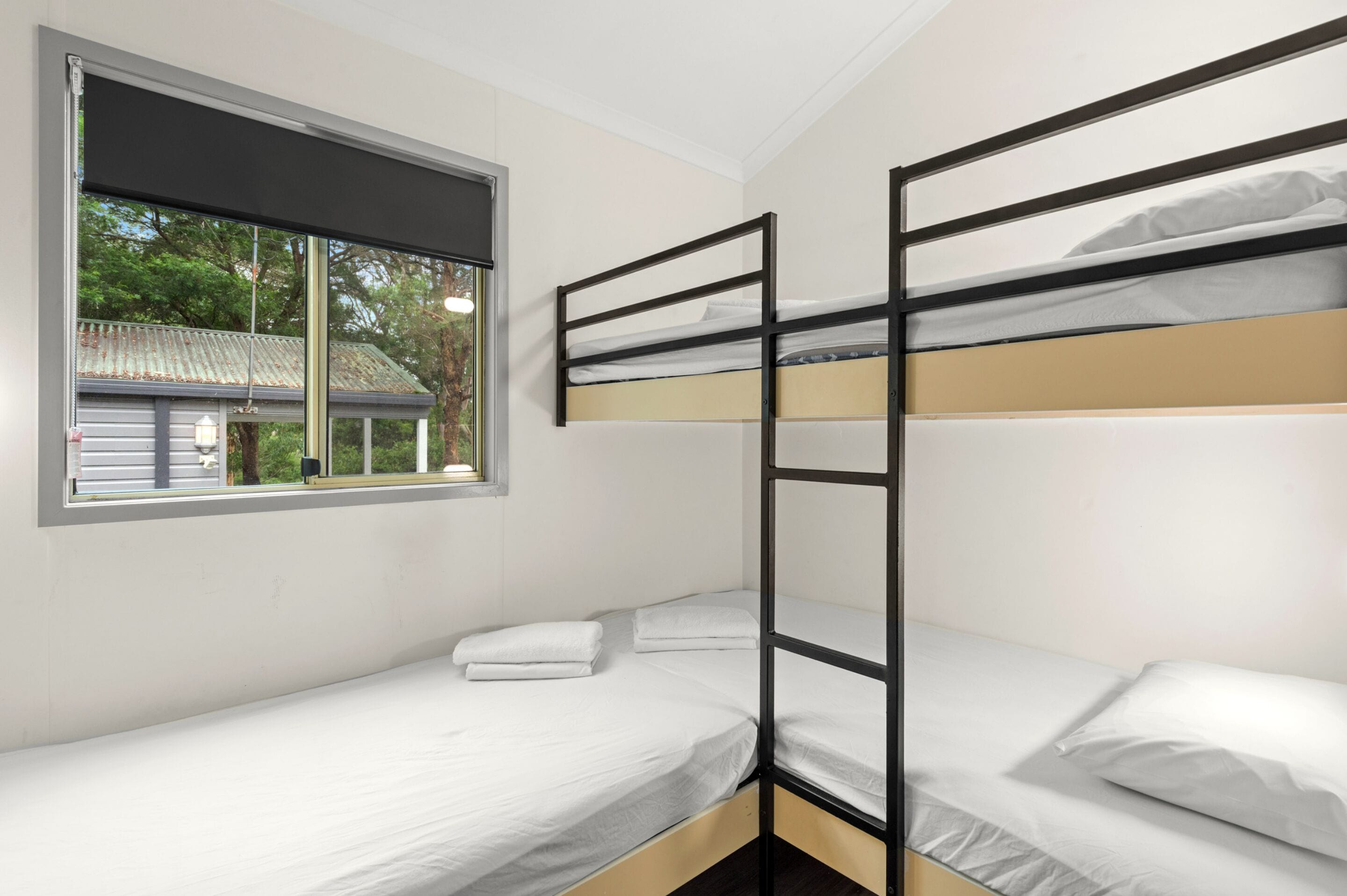A bunk bed room with a window overlooking a house.