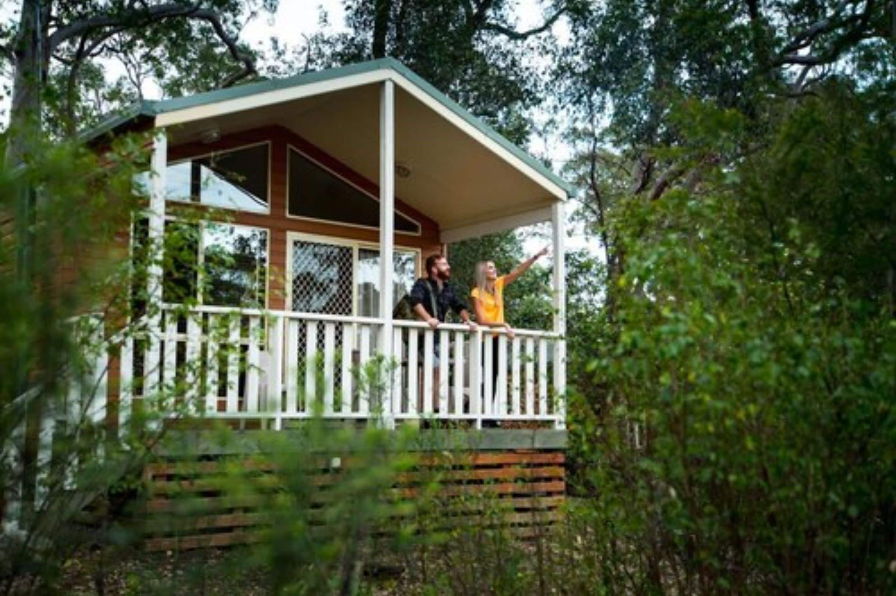 A cabin with a balcony, surrounded by trees.
