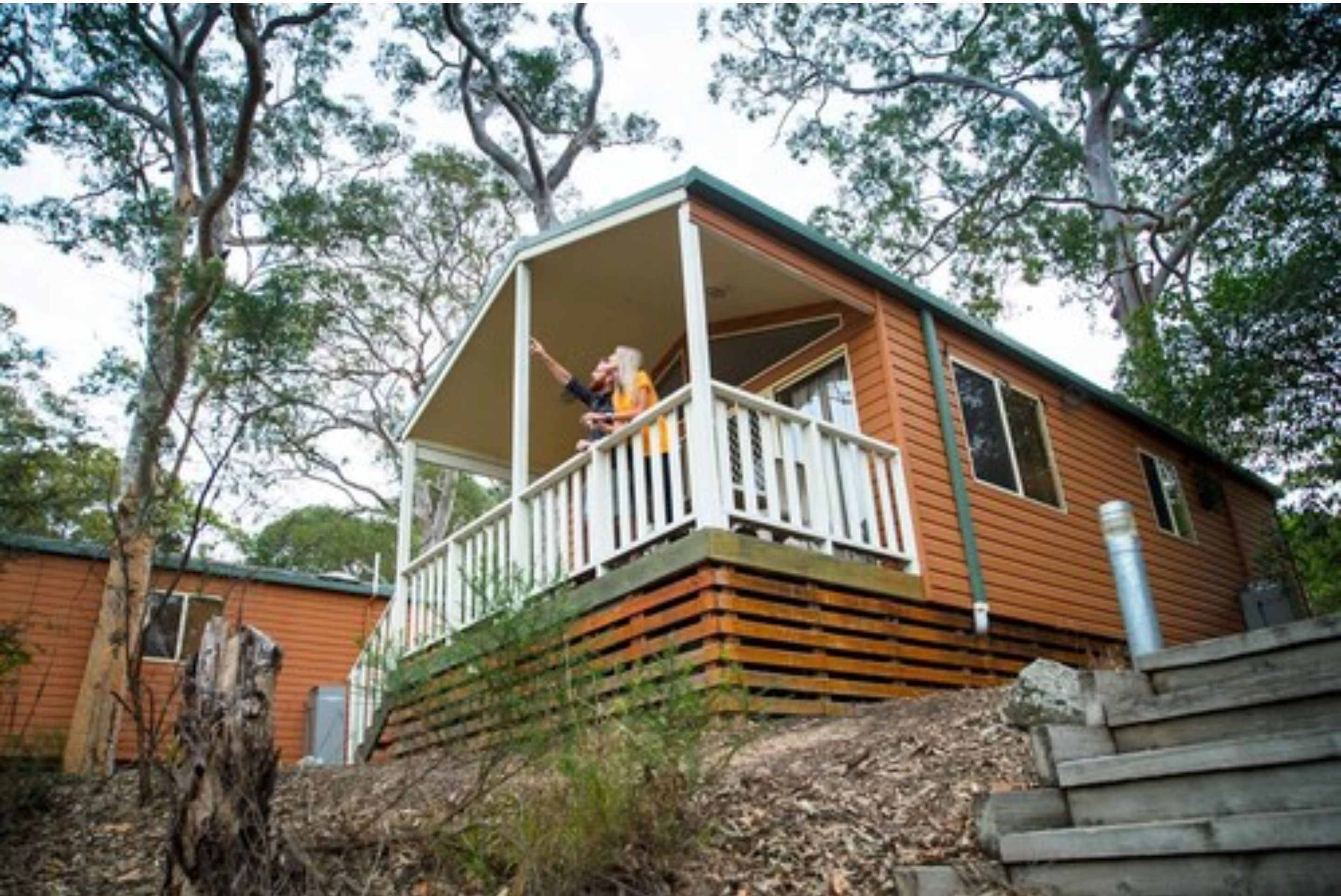 A wooden cabin with a porch and a small deck.