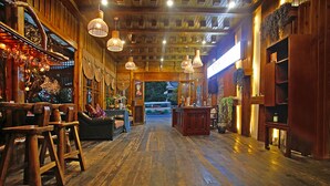Ein Holzinterieur mit einer zentralen Sitzgruppe, Holztischen und hängenden Leuchten.