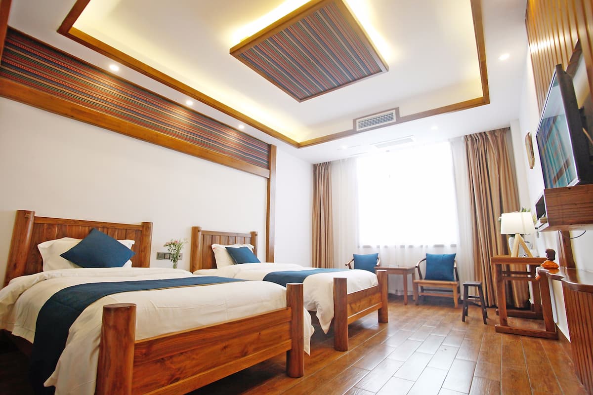 Une chambre d’hôtel avec deux lits en bois, une télévision, un bureau et une chaise.