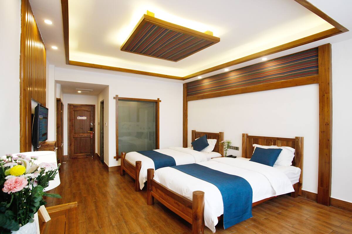 Une chambre d’hôtel avec deux lits en bois, un plafond en bois et un plancher en bois.