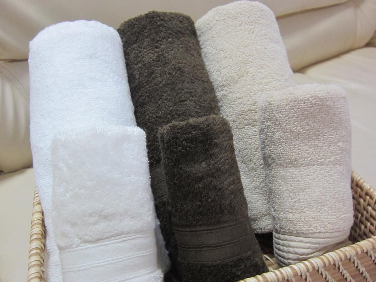 A basket containing rolled towels in various colors.