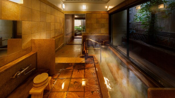 A modern bathroom with a wooden floor, a large mirror, and a bench.