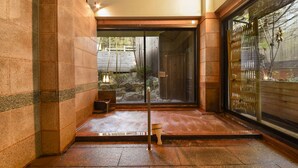 A traditional Japanese room with tatami flooring, a sliding door, and a stone wall.